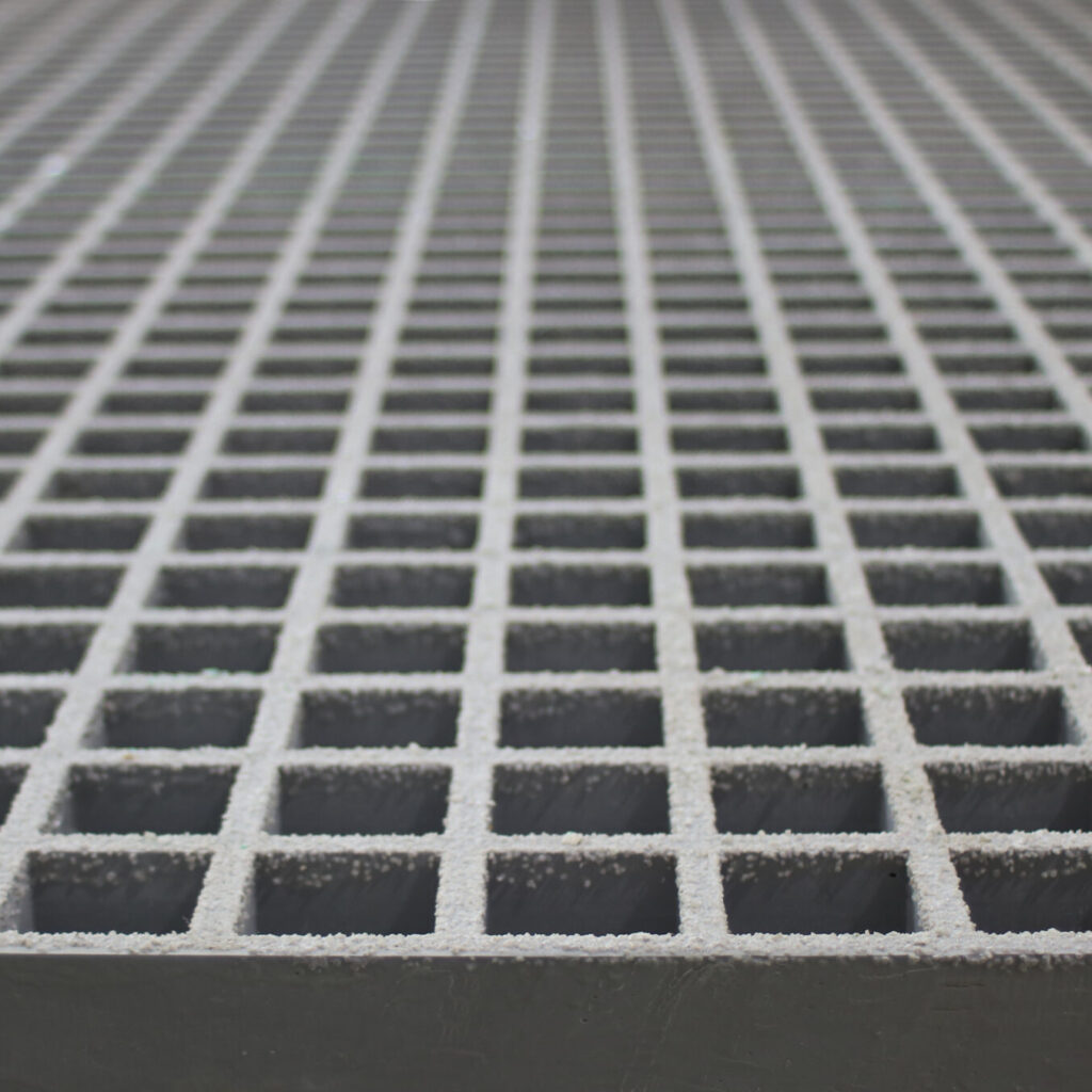 A close-up of a panel of QuartzGrip GRP Open Mesh Grating in grey showing the slip-resistant, gritted finish